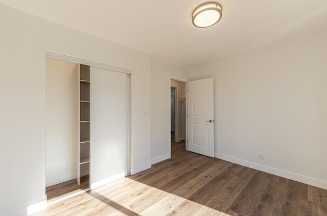 unfurnished bedroom with wood-type flooring and a closet