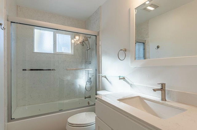 full bathroom with bath / shower combo with glass door, toilet, and vanity