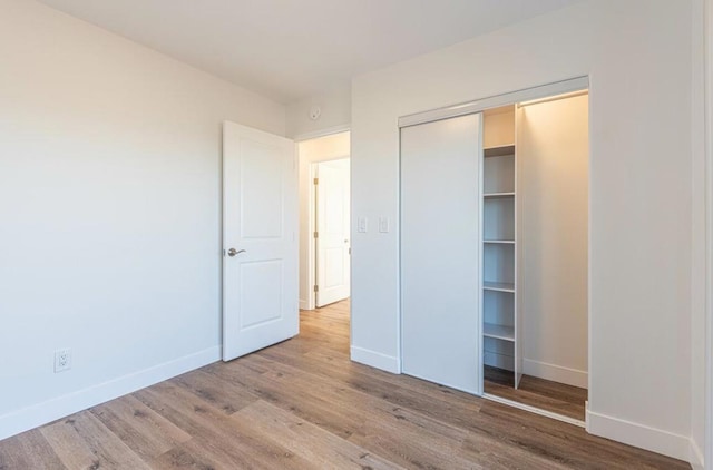 unfurnished bedroom featuring light hardwood / wood-style flooring and a closet