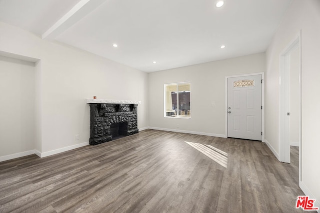 unfurnished living room featuring beam ceiling, wood-type flooring, and a fireplace