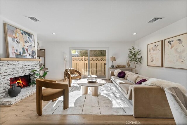 living room featuring a brick fireplace and light hardwood / wood-style floors