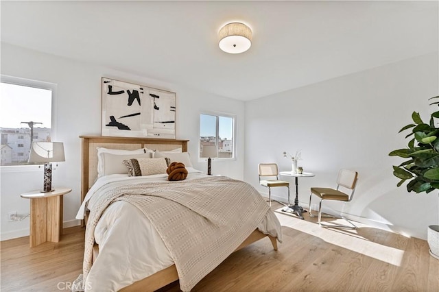 bedroom with light hardwood / wood-style floors and multiple windows