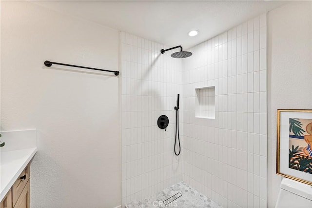 bathroom with toilet, vanity, and a tile shower