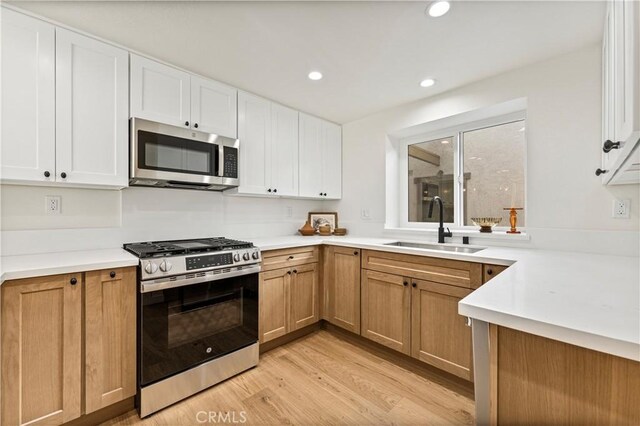 kitchen featuring light hardwood / wood-style floors, sink, white cabinets, and appliances with stainless steel finishes