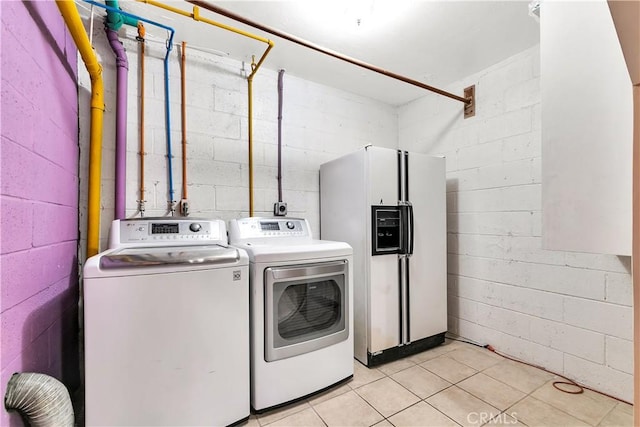 washroom with concrete block wall, laundry area, and independent washer and dryer