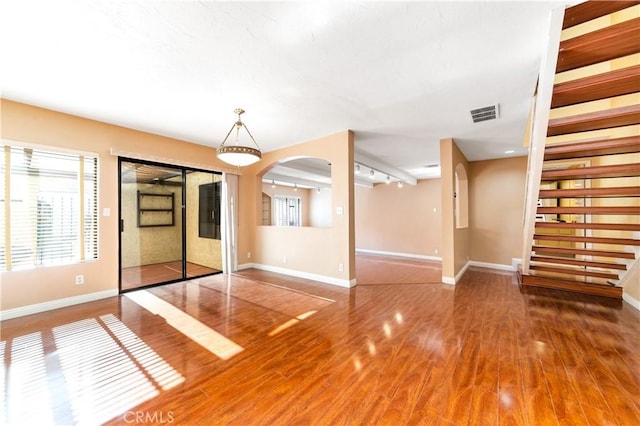 interior space featuring arched walkways, wood finished floors, visible vents, and baseboards