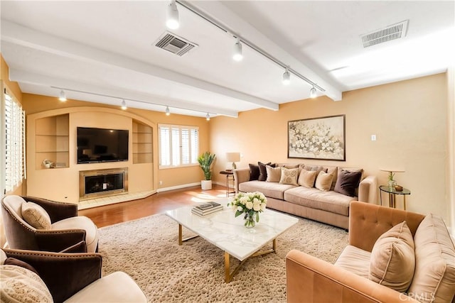 living room featuring hardwood / wood-style flooring, beamed ceiling, and built in shelves