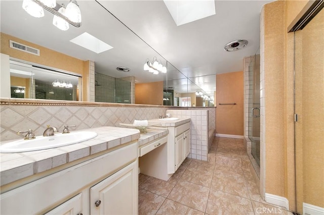 bathroom with a stall shower, visible vents, a sink, and a skylight