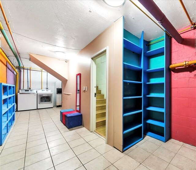 interior space featuring concrete block wall, tile patterned floors, a textured ceiling, and separate washer and dryer