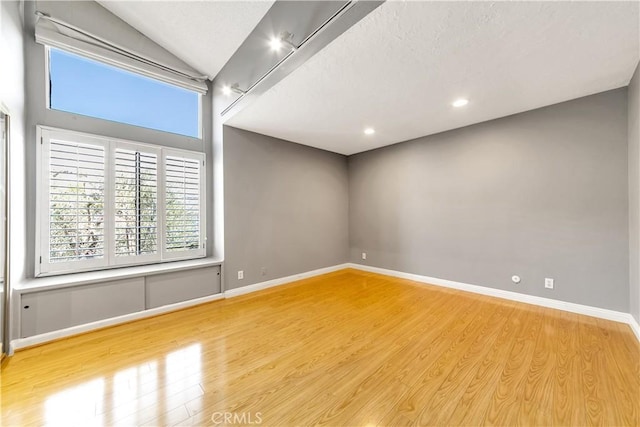 spare room with recessed lighting, vaulted ceiling, baseboards, and wood finished floors