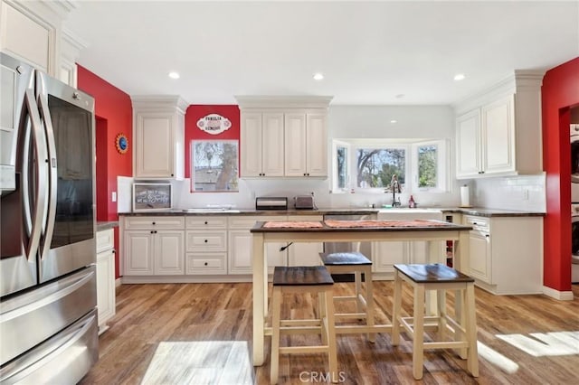 kitchen featuring stainless steel refrigerator with ice dispenser, light hardwood / wood-style floors, and white cabinets