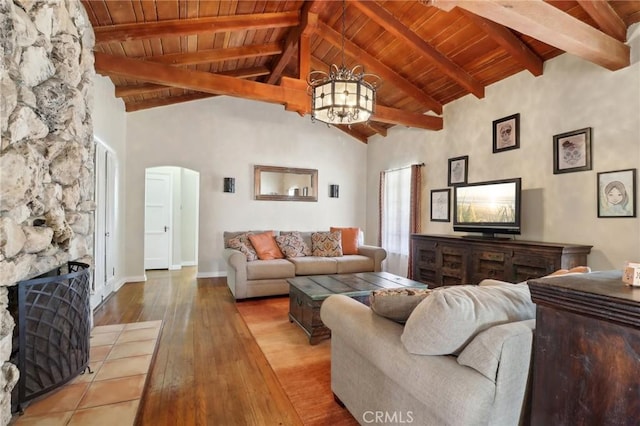 living room featuring a fireplace, hardwood / wood-style floors, beamed ceiling, high vaulted ceiling, and a chandelier