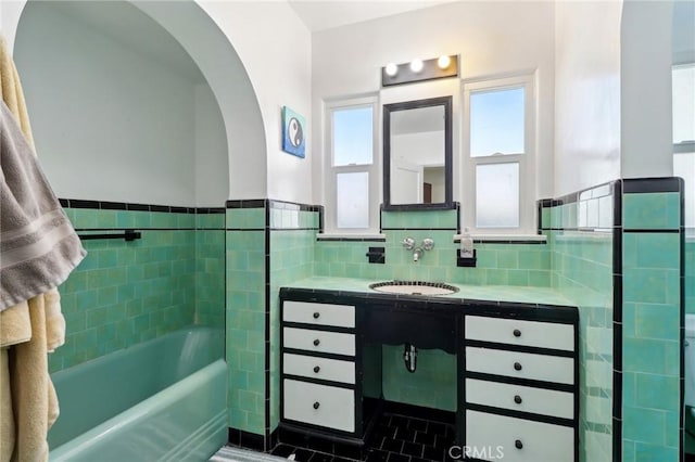 bathroom with tile walls, a washtub, and vanity