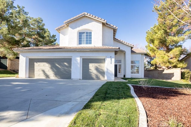 mediterranean / spanish home with stucco siding, an attached garage, driveway, and fence