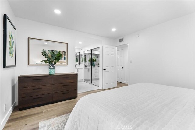 bedroom with ensuite bath and light wood-type flooring