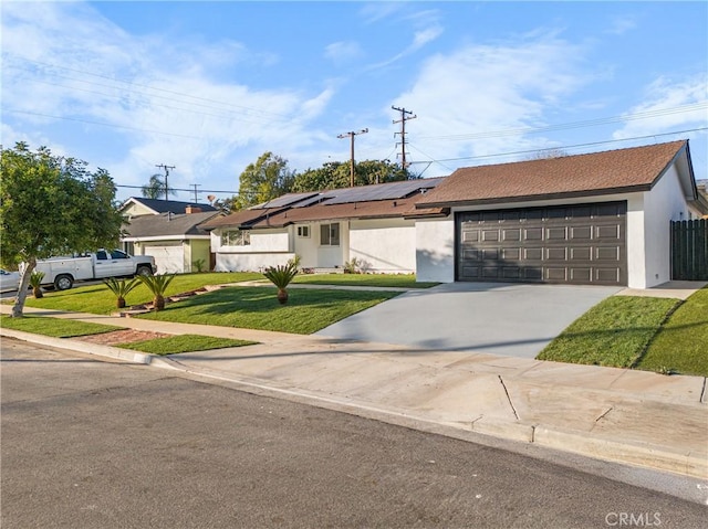 ranch-style home with a front yard, a garage, and solar panels