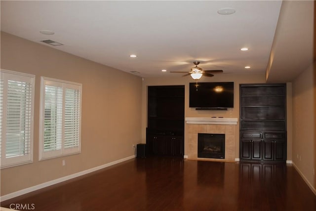 unfurnished living room featuring ceiling fan, dark wood-type flooring, and a fireplace