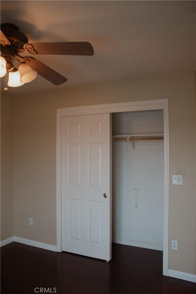 unfurnished bedroom featuring ceiling fan, dark wood-type flooring, and a closet