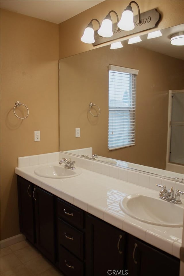 bathroom with a shower with shower door, tile patterned floors, and vanity