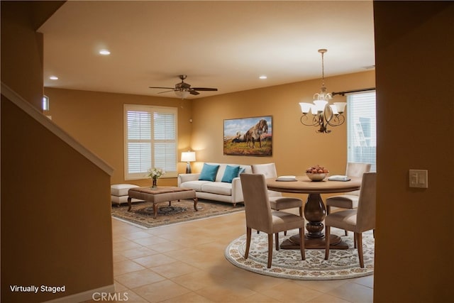 tiled dining room featuring ceiling fan with notable chandelier