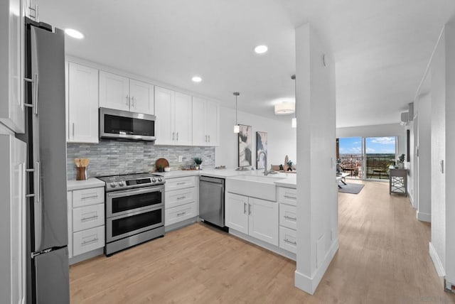 kitchen with tasteful backsplash, sink, hanging light fixtures, stainless steel appliances, and white cabinets