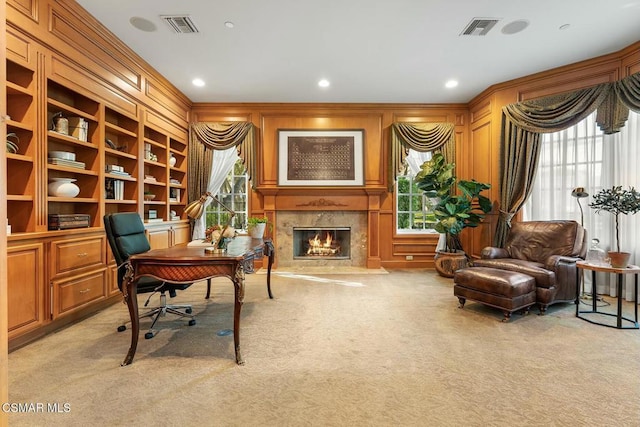 office featuring wood walls, built in shelves, light carpet, and a premium fireplace