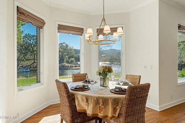 dining space with a chandelier, a water view, light hardwood / wood-style flooring, and ornamental molding