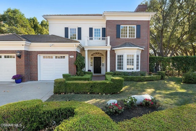 view of front of property featuring a balcony, a garage, and a front lawn