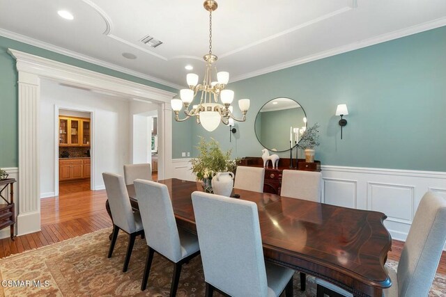 dining area featuring crown molding, wood-type flooring, and a chandelier