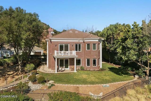 rear view of property featuring a balcony and a lawn