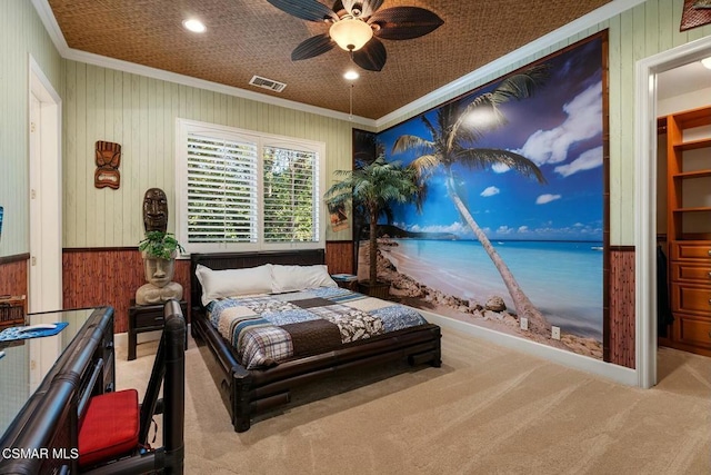 bedroom with ceiling fan, light colored carpet, crown molding, and wooden walls