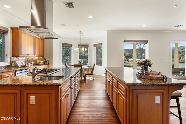 kitchen with hanging light fixtures, a center island with sink, dark hardwood / wood-style flooring, and island exhaust hood