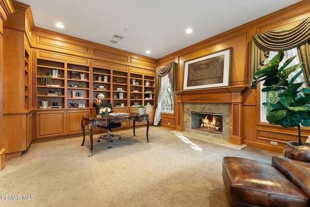 carpeted office space with built in features, wood walls, ornamental molding, and a fireplace