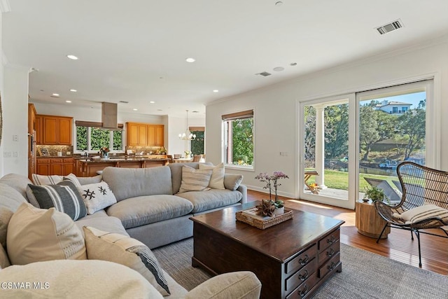 living room featuring hardwood / wood-style flooring, crown molding, and a chandelier