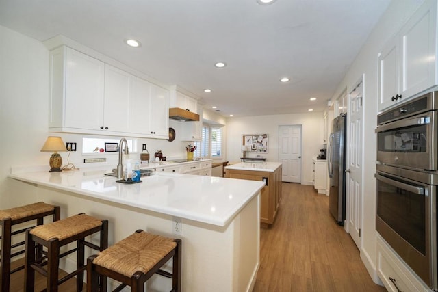 kitchen with appliances with stainless steel finishes, white cabinets, kitchen peninsula, and a kitchen bar