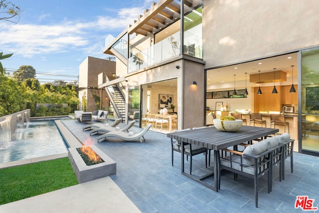 view of patio featuring pool water feature and a fire pit