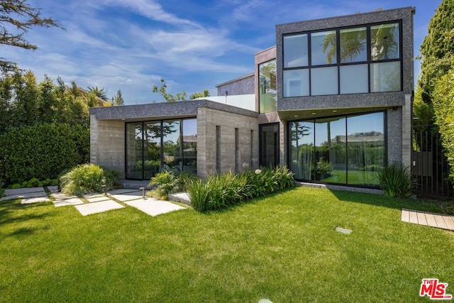 rear view of house featuring a sunroom and a lawn