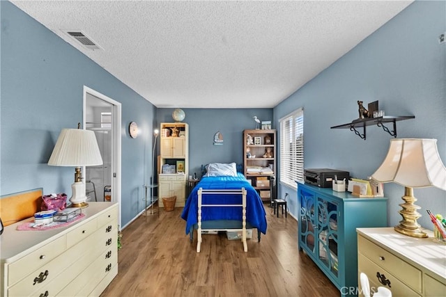 bedroom featuring light hardwood / wood-style flooring and a textured ceiling