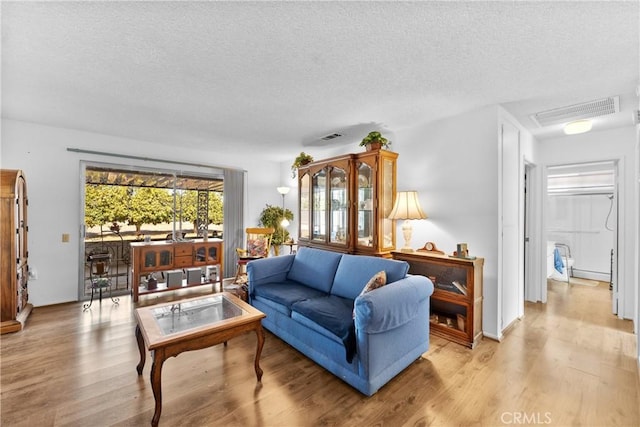 living room with a textured ceiling and light wood-type flooring