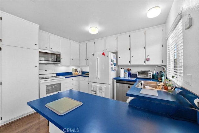 kitchen with stainless steel appliances, white cabinetry, wood-type flooring, and sink