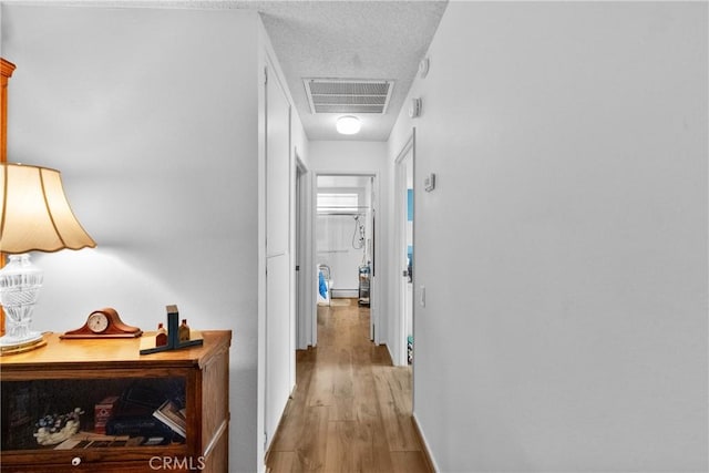 hallway featuring a textured ceiling and light hardwood / wood-style flooring