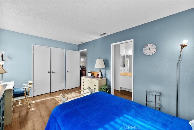 bedroom featuring wood-type flooring, a closet, a textured ceiling, and ensuite bathroom