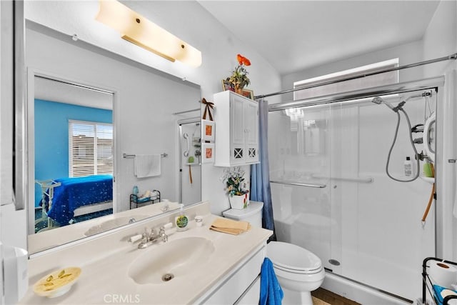 bathroom featuring toilet, vanity, and a shower with shower door