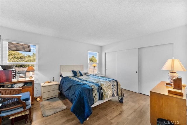 bedroom with light hardwood / wood-style floors, a closet, and a textured ceiling