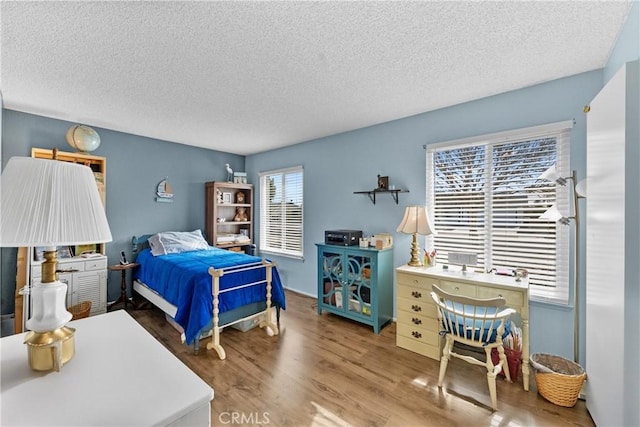 bedroom featuring multiple windows, hardwood / wood-style flooring, and a textured ceiling