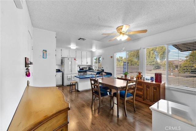 dining area featuring ceiling fan, a healthy amount of sunlight, dark hardwood / wood-style flooring, and a textured ceiling