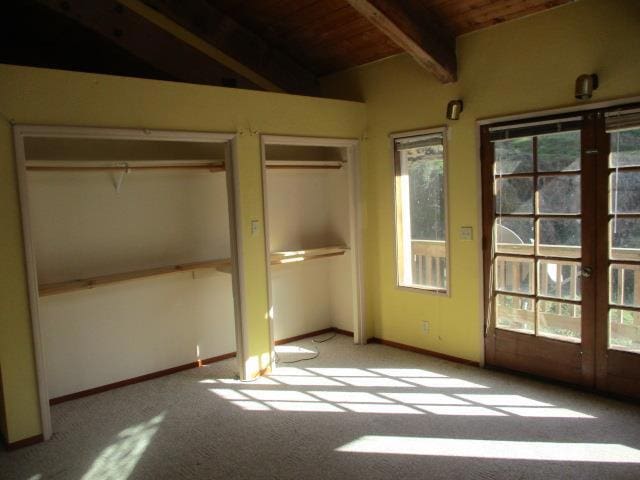 unfurnished bedroom featuring light carpet, vaulted ceiling with beams, french doors, and wood ceiling