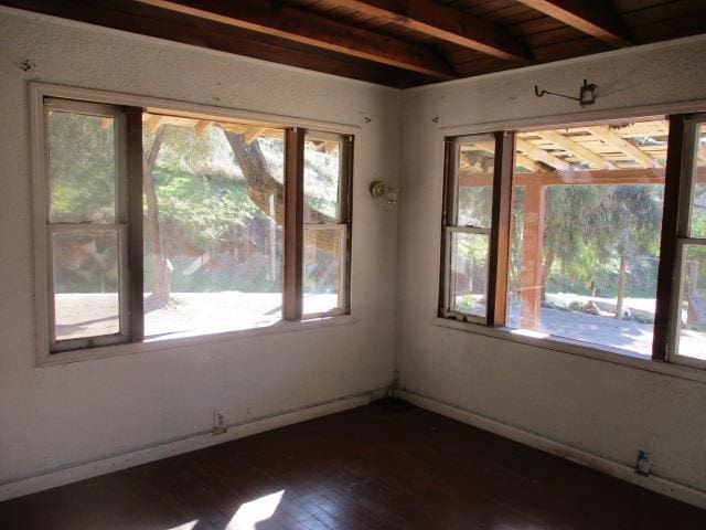 empty room featuring dark hardwood / wood-style flooring, wood ceiling, and beam ceiling