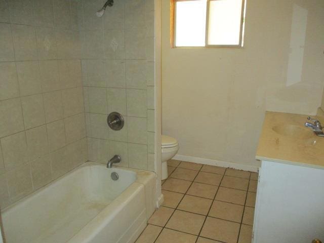 full bathroom with toilet, tile patterned flooring, tiled shower / bath, and vanity