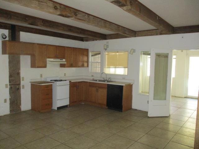 kitchen featuring stove, black dishwasher, beam ceiling, and sink